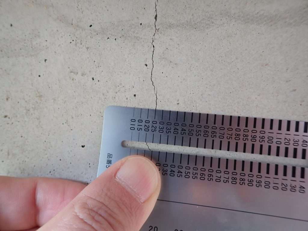 クラックスケールを用いて基礎のひび割れ幅を測定する様子