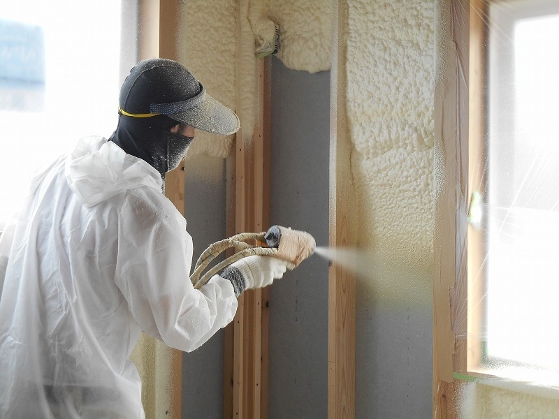吹き付けウレタンフォームを壁内に施工している専門業者の作業風景