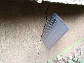 基礎のクラックに名刺を差し込み0.5mm以上の隙間を確認する様子