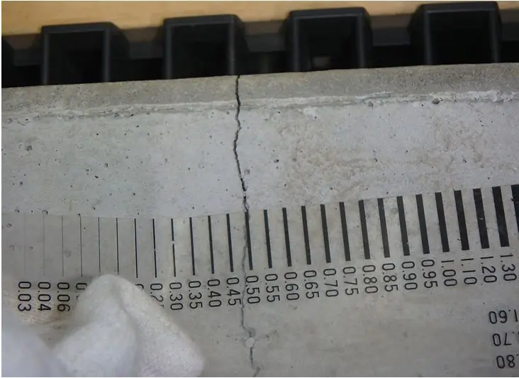 基礎コンクリートに発生した幅0.5mm以上の構造クラックとクラックスケールでの計測の様子