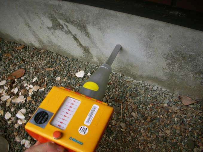 シュミットハンマーを使用してコンクリート基礎の推定圧縮強度を測定する様子